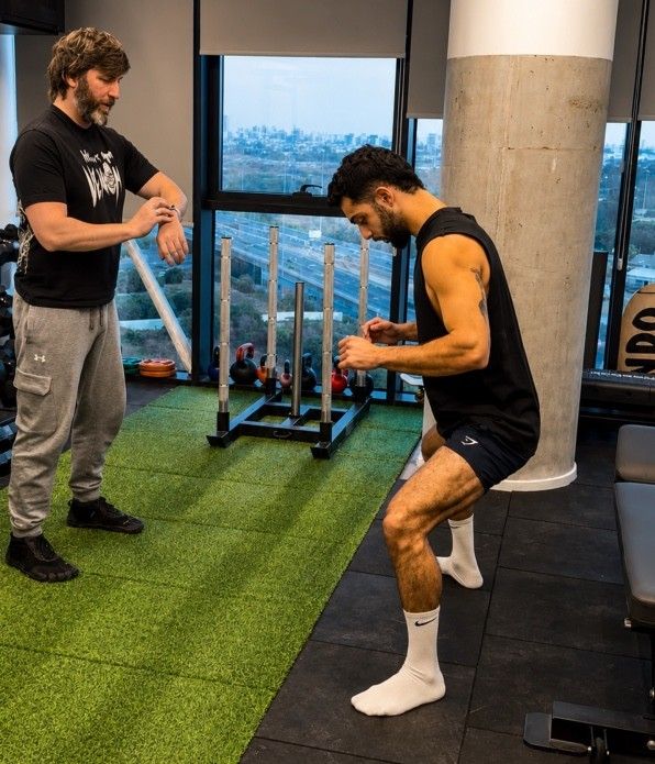מטופל בתרגול שיקומי בקליניקת Recovery Center, ליד חלון בקומה 8, בהדרכת מאמן